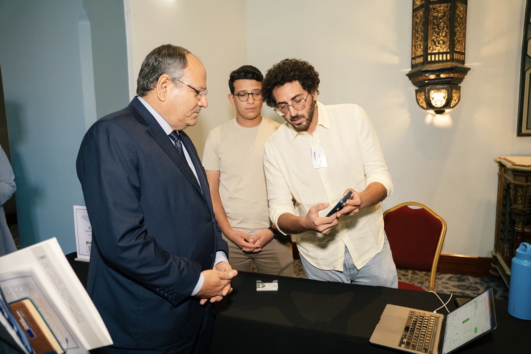 Seif Salama demonstrating the GeneinaOS app on a phone to a senior official